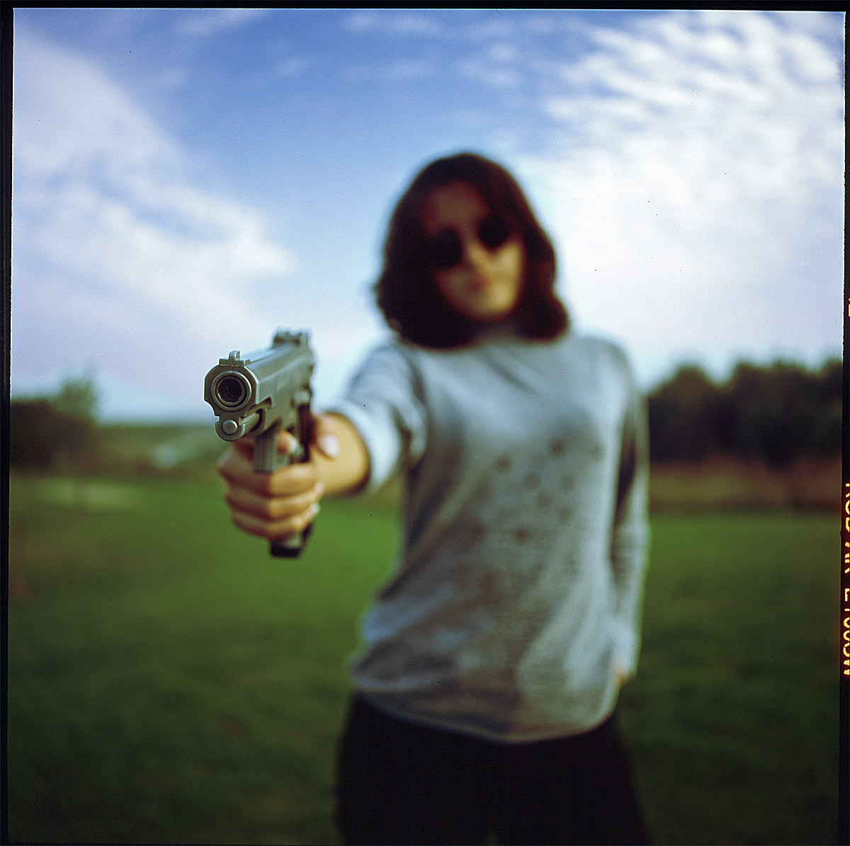Girl dark hear and glases pointing gun